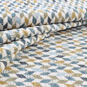 May include: Close-up of a white fabric with a geometric pattern of blue and gold leaves. The fabric is folded in half, showing the pattern on both sides.