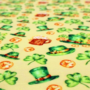 Peut inclure: Un tissu jaune clair avec un motif répété de chapeaux de lutin verts, de trèfles, de chopes de bière et de pièces d'or. Le motif sur le thème de la Saint-Patrick présente des illustrations de style aquarelle.