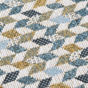 May include: A close-up of a fabric with a repeating pattern of blue, white and yellow geometric shapes. The fabric has a textured surface.