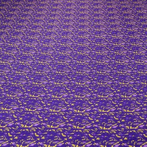 Peut inclure: Un tissu violet présentant un motif géométrique répétitif composé de formes abstraites jaunes et violet foncé. Le textile affiche une disposition dense et cohérente de ces motifs angulaires sur toute la surface visible, créant un aspect texturé.