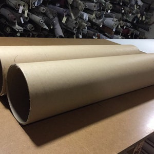May include: Two large brown cardboard tubes lying on a wooden surface.