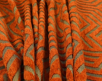 May include: Close-up of a rust-colored fabric with a woven pattern of brown lines. The fabric has a textured, corduroy-like surface.