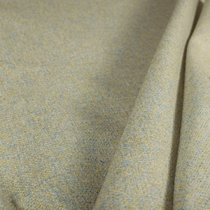 Puede incluir: Primer plano de una tela texturizada con un patr&oacute;n tejido. La tela es principalmente de color beige claro, con motas amarillas y azules. La tela est&aacute; doblada, mostrando la textura y la ca&iacute;da del material.