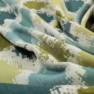 May include: Close-up of a fabric with a textured, abstract pattern in shades of green, blue, and white.