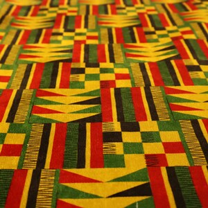 Op de afbeelding: Close-up van een levendige stof met een herhalend geometrisch patroon. Het ontwerp bevat blokken geel, rood, groen en zwart, waardoor een gedurfde en kleurrijke stof ontstaat. De textuur van de stof lijkt zacht, met een lichte glans.
