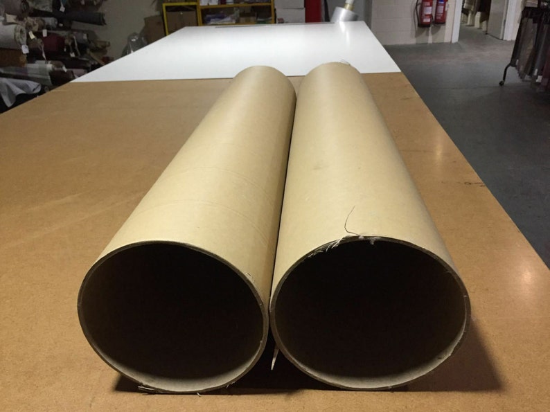 May include: Two large brown cardboard tubes, lying side by side on a wooden surface.