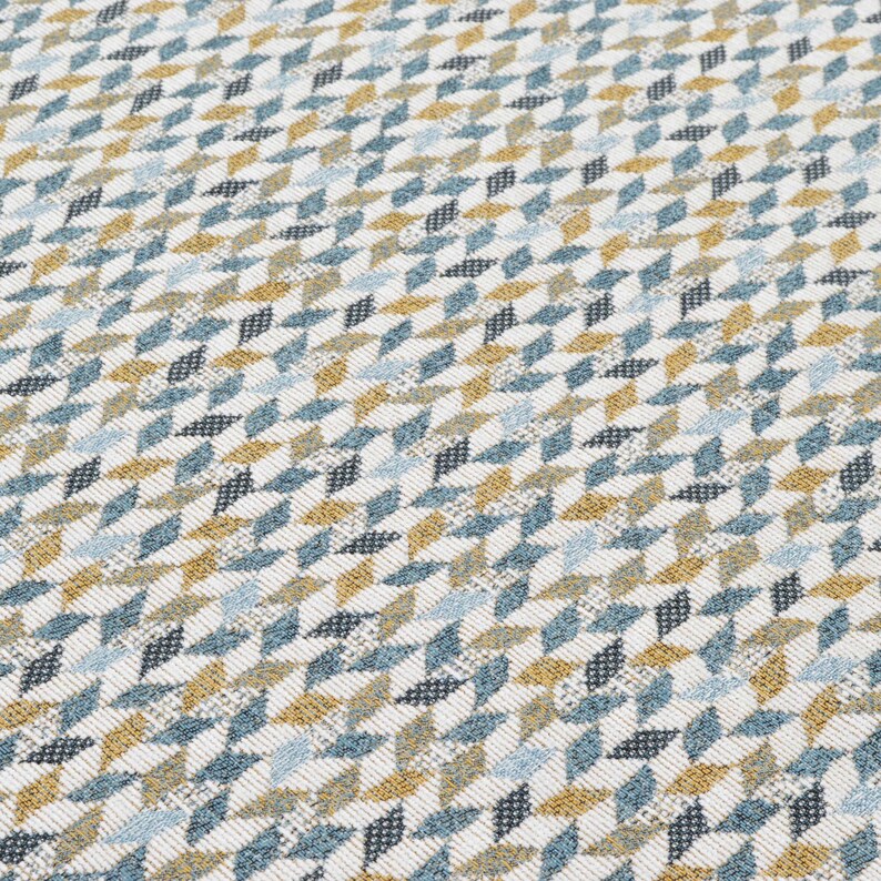 May include: A white fabric with a geometric pattern of blue, gold, and black triangles.