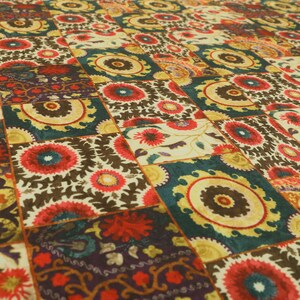 May include: A colourful fabric with a repeating pattern of stylised flowers and circles in shades of red, yellow, green, and brown.