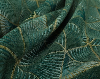 May include: Close-up of a green fabric with a geometric pattern of gold and green leaves. The fabric has a textured surface and a subtle sheen.