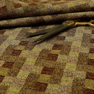 Peut inclure: Gros plan sur un tissu à motifs marrons et dorés avec une paire de ciseaux posée dessus. Le tissu présente un motif à carreaux avec une surface texturée.