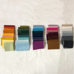 May include: A collection of fabric swatches in various colours, including red, orange, yellow, green, blue, purple, brown, grey, and white. The swatches are arranged in rows, with each row containing a different colour.