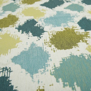 May include: A white fabric with a repeating pattern of abstract shapes in shades of teal, green, and yellow.