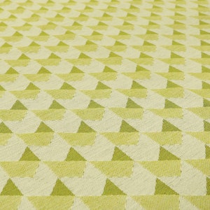 May include: A close-up of a fabric with a geometric pattern of green triangles on a white background.