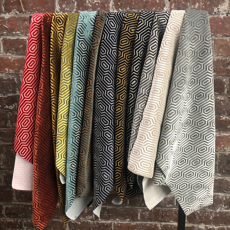 May include: A collection of 10 fabric swatches featuring a geometric pattern in various colours, including red, orange, yellow, green, blue, black and grey.