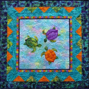 May include: A quilt with a blue background and a border of orange, green, and purple. Three colorful sea turtles are swimming in the center of the quilt.