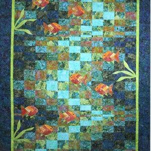 May include: A quilt with a checkered pattern in shades of blue, green, and brown. The quilt features a design of orange fish swimming in a pattern.