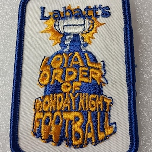 May include: Embroidered patch with a blue border and a white background. The patch features the text "Labatt's" in blue, above a blue and gold design. Below the design, the text reads "ROYAL ORDER OF MONDAYNIGHT FOOTBALL" in gold.