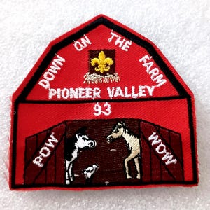 May include: Embroidered red patch with a barn design. The patch features the text "DOWN ON THE FARM" and "PIONEER VALLEY 93". Inside the barn are embroidered images of a cow, a foal, and a horse. The words "POW" and "WOW" are also present.