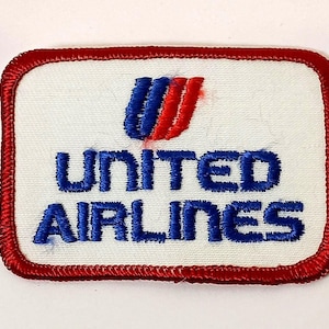 May include: Rectangular patch with a white background and a red border. The patch features the United Airlines logo in blue and red, with the words "UNITED AIRLINES" embroidered in blue.