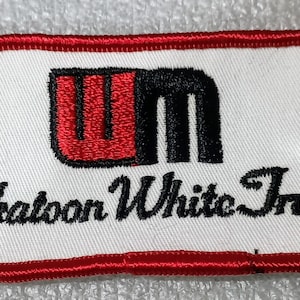 May include: Embroidered patch with a white background and a red border. The patch features the text "Saskatoon White Trucks" in black script and a red and black logo.