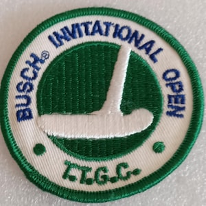 May include: Embroidered patch with a white golf club design on a green background. The patch features the text "BUSCH INVITATIONAL OPEN" in blue and "T.G.C." in green, set against a white border.