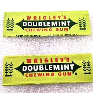 May include: Two vintage Wrigley's Doublemint chewing gum wrappers. The wrappers are light green with red text and a black arrow design. The text reads "WRIGLEY'S DOUBLEMINT CHEWING GUM" and "Keep foil wrapper to put gum in after use."