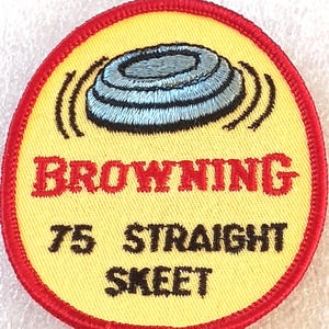 May include: Embroidered patch with a yellow background and a red border. The patch features a blue and gray clay target design, the word "BROWNING" in red, and the text "75 STRAIGHT SKEET" in black.