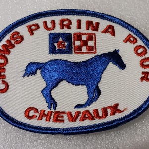 May include: Oval patch with a blue horse silhouette, the text "PURINA POUR CHEVAUX" in red, and "CHOWS" in red. The patch has a blue border and a white background.