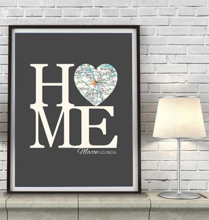 May include: A gray and white print with the word "HOME" in large white letters. A heart-shaped map of Macon, Georgia is in the center of the print. The text "Macon GEORGIA" is below the heart.