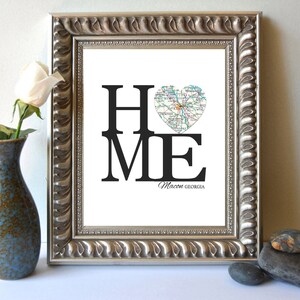 May include: A framed print with the word "HOME" in black text, with the "O" replaced by a heart-shaped map of Macon, Georgia. The text "Macon, Georgia" is printed below the word "HOME".
