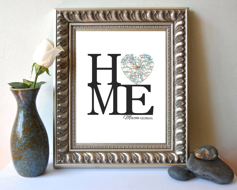 May include: A framed print with the word "HOME" in black text, with the "O" replaced by a heart-shaped map of Macon, Georgia. The text "Macon, Georgia" is printed below the word "HOME".