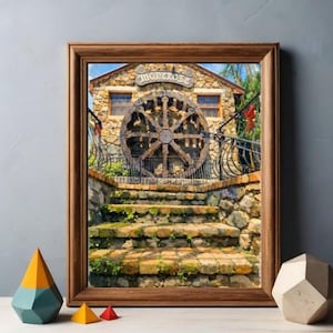 May include: A framed print of a stone building with a large wooden water wheel. The building has a sign that reads "Montrose". A brick staircase leads up to the building. Decorative geometric shapes sit in front of the frame.