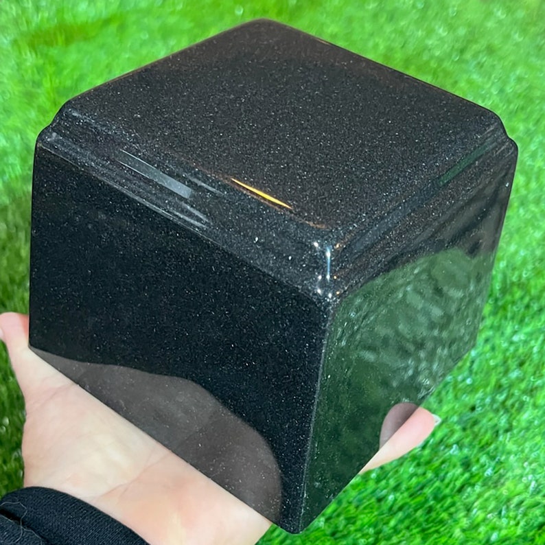 May include: A black square shaped granite cremation urn.