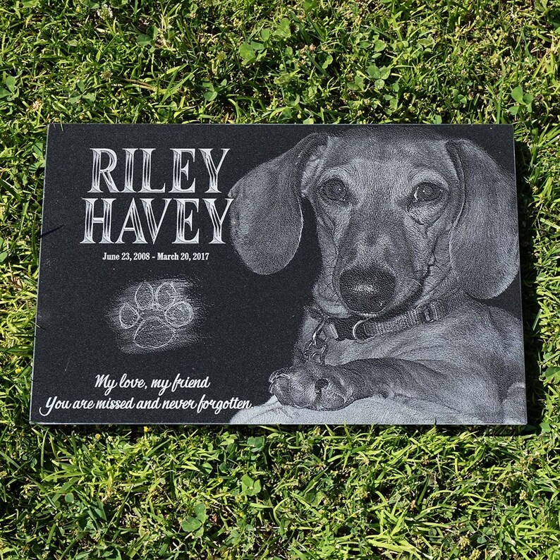 Puede incluir: Un monumento conmemorativo para mascotas de granito negro con el nombre "RILEY HAVEY" y las fechas 23 de junio de 2008 - 20 de marzo de 2017. Presenta una imagen grabada detallada de un perro y una huella de pata. La inscripci&oacute;n dice "Mi amor, mi amigo, Te echamos de menos y nunca te olvidaremos."