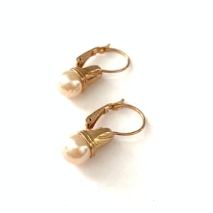 May include: A pair of gold hoop earrings with a single pearl dangling from each hoop.