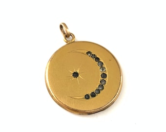 May include: A gold locket pendant with a crescent moon and star design. The moon is outlined with small black stones.