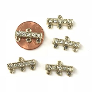May include: Five gold-tone metal connector pieces with clear rhinestones. Each connector has three loops for attaching jewelry.