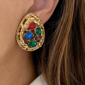 May include: Gold tone clip-on earrings with a cluster of red, blue, green, and purple rhinestones.