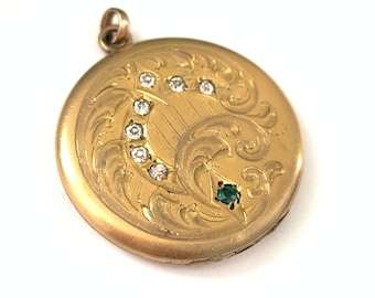 Può includere: Un medaglione d'oro con un designo inciso dettagliato che presenta una forma di luna crescente con una fila di pietre chiare e un'unica pietra verde.