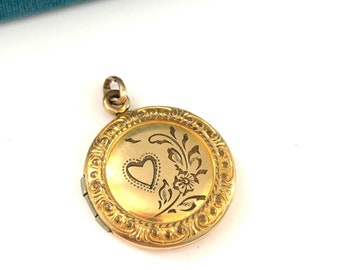 Puede incluir: Un medallón de oro con un diseño floral y un corazón grabado en la parte delantera. El medallón está sobre un fondo blanco.