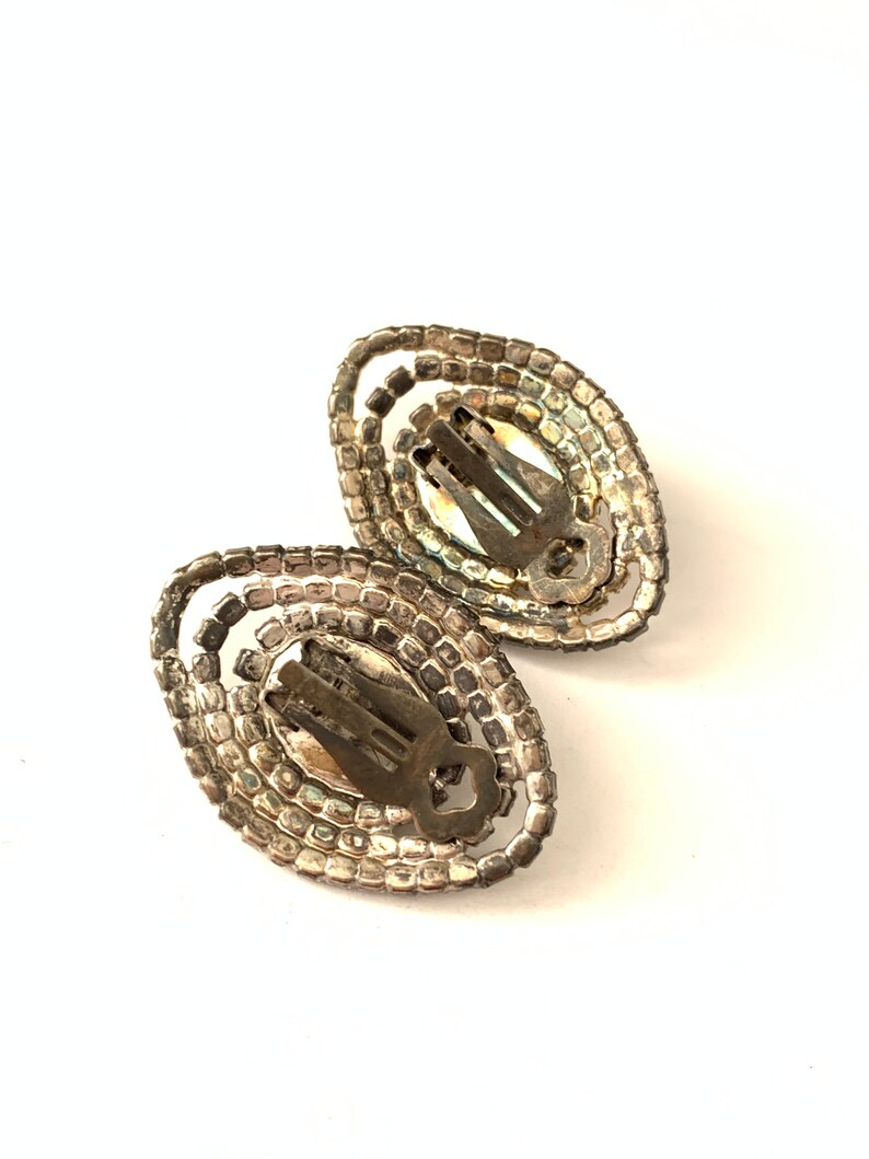 Op de afbeelding: Een paar zilverkleurige clip-on oorbellen met ovale strass.