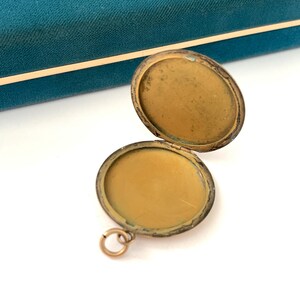 Puede incluir: Un medall&oacute;n de oro con una tapa con bisagras, abierto para revelar un interior vac&iacute;o. El medall&oacute;n tiene un peque&ntilde;o bucle para sujetar una cadena.