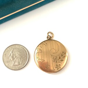 Puede incluir: Un medall&oacute;n de oro con un dise&ntilde;o floral. El medall&oacute;n es aproximadamente del tama&ntilde;o de una moneda de euro.