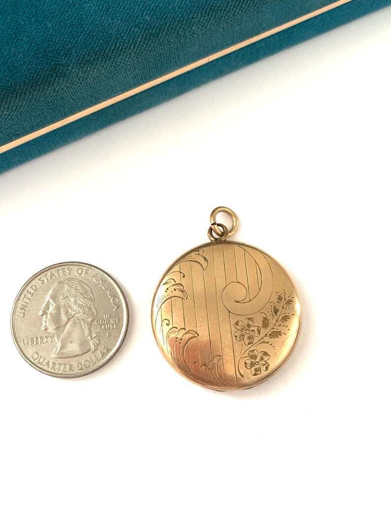 Puede incluir: Un medall&oacute;n de oro con un dise&ntilde;o floral. El medall&oacute;n es aproximadamente del tama&ntilde;o de una moneda de euro.