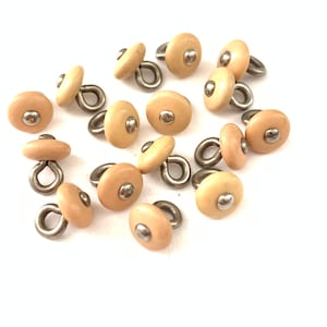 May include: A group of 15 beige plastic buttons with a silver loop and a silver dot in the center.