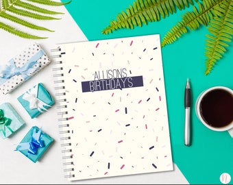 May include: A white notebook with a spiral binding. The cover has a confetti pattern in pink, red, and blue. The text "Allison's Birthday's" is printed in black on a navy blue rectangle.