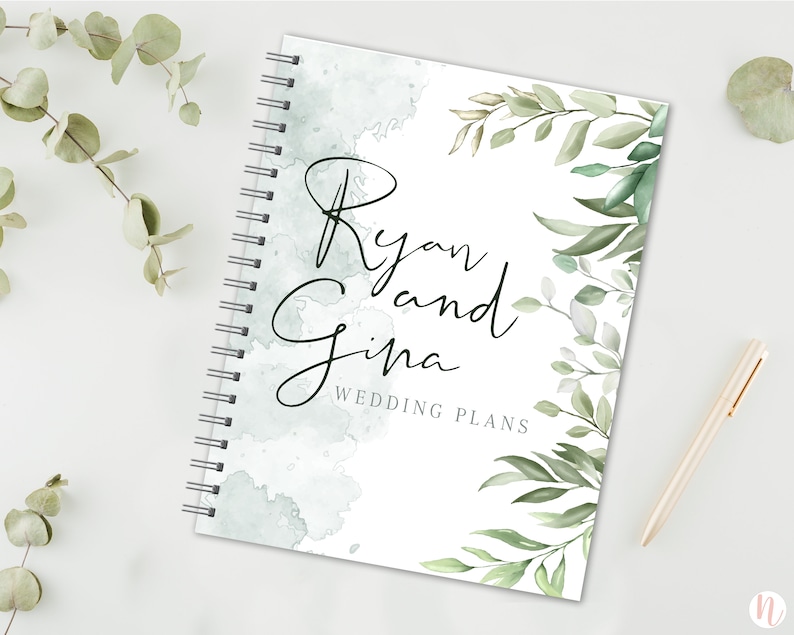 May include: A white wedding planner with a watercolor background and green foliage. The text "Ryan and Gina Wedding Plans" is printed on the front.