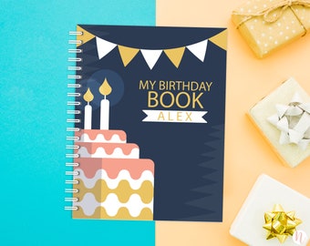 May include: A blue spiral bound notebook with a birthday cake and candles on the cover. The text on the cover reads "My Birthday Book Alex".