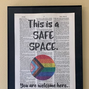 This is a safe space. You are welcome here printed on a dictionary page with an image of rainbow and trans colored circle