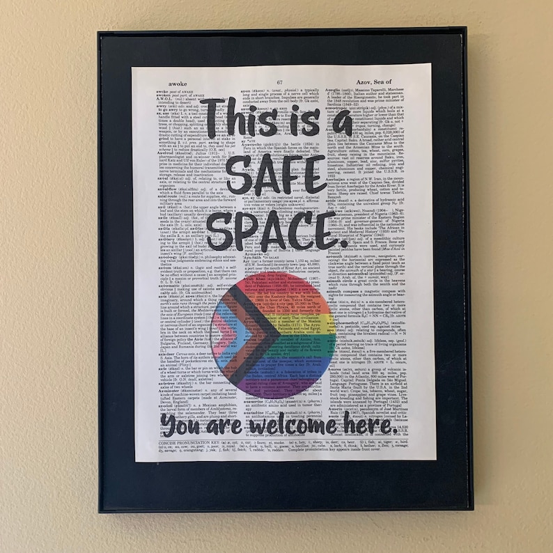 This is a safe space. You are welcome here printed on a dictionary page with an image of rainbow and trans colored circle